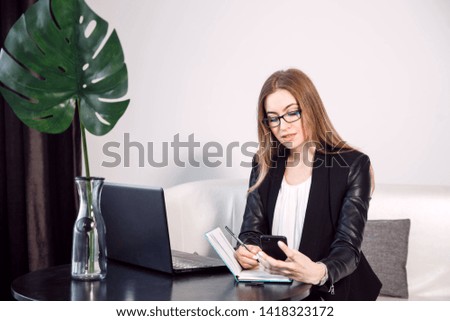 Very busy young businesswoman reviewing some work and talking on her cell phone