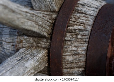  very Close look of a weathered old  cracked and rusted woodened spoked wagon wheel with axle and hub reinforce with metal rings