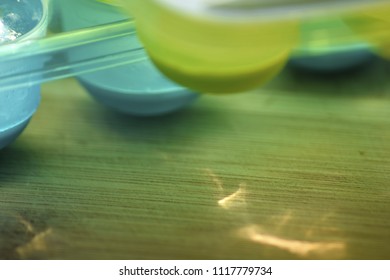 Very Close Up On A Part Of A Blurred Spherical Shape Ice Cube Bucket, Placed On A Wooden Surface Sprayed With Light Reflections Giving An Abstract Impression Of Freshness