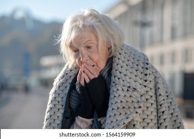 Very cold outside. Grey-haired homeless pensioner feeling very cold and unprotected outside
