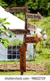 A Very Cool And Unique Wedding Sign Showing Guests Directions To Various Areas And A Tent In The Background.