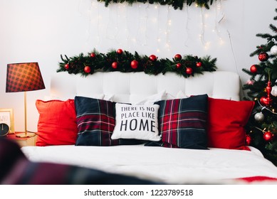 Very cozy and modern Christmas interior design idea with pillows and Christmas lights. Words on a pillow say "There is no place like home".