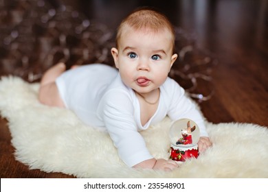 Very Cute Baby Lying On The Floor On The Background Of Christmas Lights And Displays Language