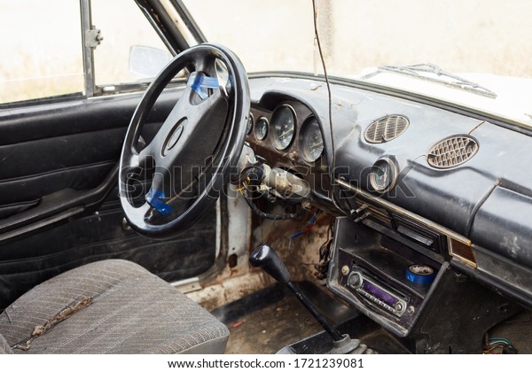 The\
very damaged interior of an old car from the\
1980s