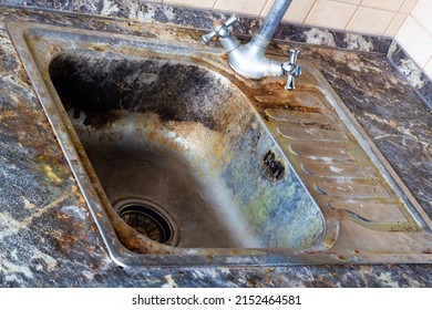 Very Dirty Kitchen Sink. The Kitchen And Dishwashing Area Need To Be Cleaned With A Cleaning Agent. Cleaning The Kitchen Sink. Detergents For The Cooking Room. Old Faulty Water Faucet. Close-up