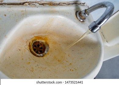 very dirty little wash basin for hands. rusty water flows from the tap.