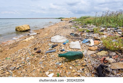 Very Dirty Seashore. Environmental Disaster From Human Negligence. Selective Focus On The Green Bottle.