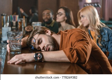 Very Drunk Young Man At Bar With Friends