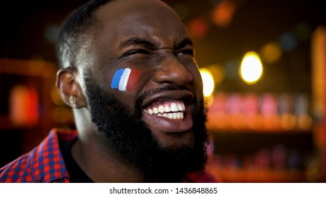 Very emotional black fan with french flag painted on cheek cheering for team - Powered by Shutterstock