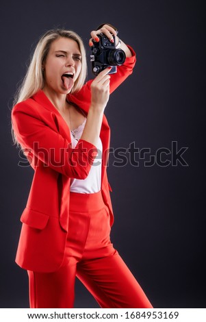 Very emotional young female photographer making funny photos, teasing fashion model, sticking her tongue out