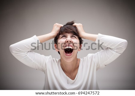 very enraged woman screaming out while pulls out her hair - angry woman concept