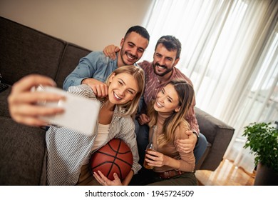 Very Excited Friends Having Fun By Watching Basketball Match At Home.