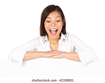 Very Excited Woman Holding Billboard / Blank Sign And Looking Down. Beautiful Mixed Race Asian / Caucasian Model. Isolated On Seamless White Background.