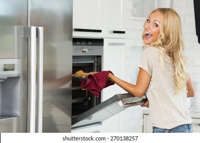 Very Expressive Commercial Woman , With Happy Face , Cooking Some Food With Oven , In Her Kitchen.