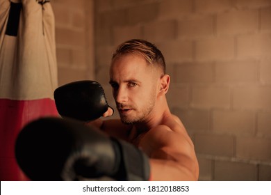 A Very Fit Young Man Punching The Boxing Bag, Vintage At Home Made Gym