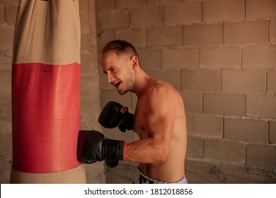 A Very Fit Young Man Punching The Boxing Bag, Vintage At Home Made Gym