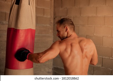 A Very Fit Young Man Punching The Boxing Bag, Vintage At Home Made Gym