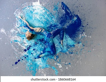 very flexible young sexy blonde woman, blue, turquoise and white painted, lies ballet dancing on the studio floor covered with paint, copy space