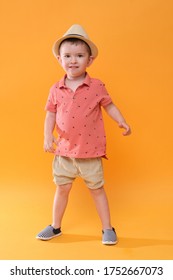 Very Happy Boy Wearing Summer Outfit. Studio Shoot On Orange Background.