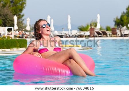 very happy woman on pink air bed in swimming pool
