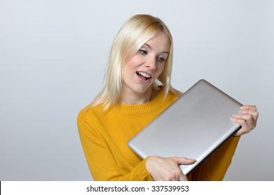 Very Happy Young Woman Holding A Brand New Laptop Computer With Mouth Open Against White Background