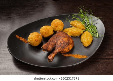 Very healthy roast duck thigh with potatoes and greens on a black plate on a wooden table serving in a restaurant. nice decoration of the dish. diet food