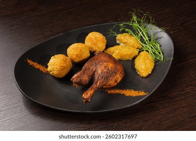 Very healthy roast duck thigh with potatoes and greens on a black plate on a wooden table serving in a restaurant. nice decoration of the dish. beautiful light on the platter
