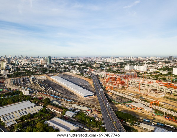 The very high aspect of new Bangkok main train\
station with cars traveling beside on highway. While train station\
is constructing on right side of highway, old trains are also\
parking on another side.