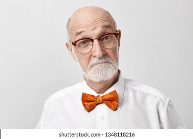 I'm very impressed. Emotional unshaven European elderly retired man wearing glasses and bow tie, raising eyebrows, astonished with impressive news. Amazement, surprise and astonishment concept