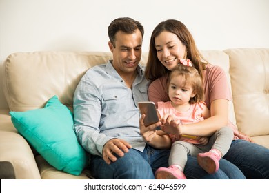 Very Interested Good Looking Hispanic Family Turning Their Attention To Moms Smartphone 