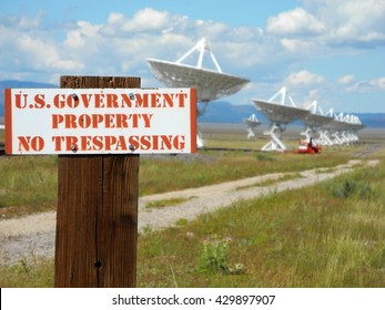 Very Large Array in New Mexico, USA. Sing marking government property. Row of satellites in the background. Cloudy day. Communication and telecommunication.