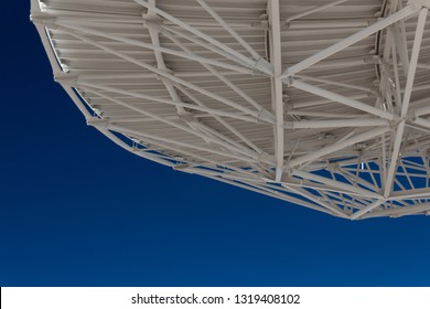 Very Large Array trusses on the underside of a radio astronomy observatory dish with blue sky beneath, creative copy space, horizontal aspect