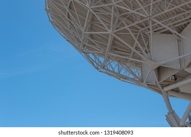 Very Large Array trusses show engineering on large dish against blue sky, backlit, science technology space, horizontal aspect