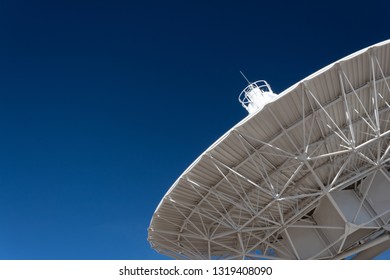 Very Large Array understructure of a radio telescope antenna dish pointing into a deep blue sky, copy space, horizontal aspect