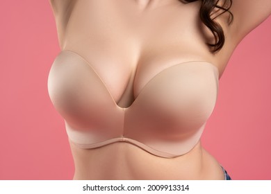 Very large breasts in a push-up bra on a pink background, close up studio shot