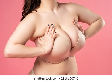 Very large breasts in a push-up bra on a pink background, close up studio shot