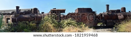 very large panoramic of an old and rusty locomotive abandoned on a driveway in Tripoli Lebanon
old abandoned and rusty locomotives, surrounded by weeds and vegetation