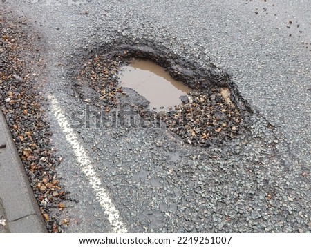 A very large pothole on a main road, Needham Market, Suffolk, England, UK during wintertime.