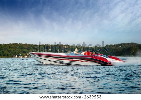 A very large speedboat crusing on a lake.