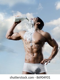 the very muscular handsome sexy guy on sky background, drink milk