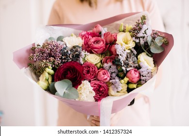 Very nice young woman holding big and beautiful bouquet of fresh roses, ranunculus, lilac peony, eustoma, eucauptus, statice, matthiola in pink and purple colors, cropped photo, bouquet close up - Powered by Shutterstock