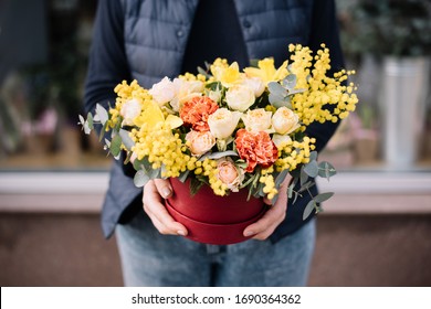 Very nice young woman holding big and beautiful floral composition of fresh roses, carnations, mimosa, eucalyptus flowers in yellow and orange colors, cropped photo, bouquet close up - Powered by Shutterstock