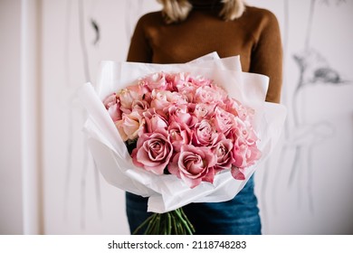 Very nice young woman holding big and beautiful mono bouquet of fresh tender pink roses, cropped photo, bouquet close up