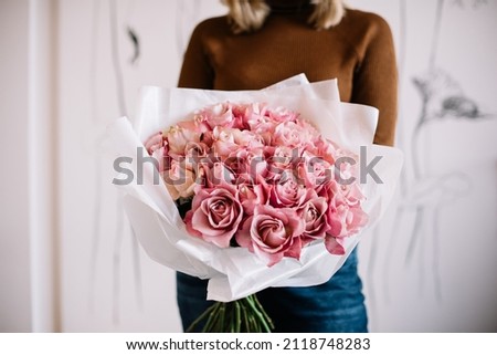 Very nice young woman holding big and beautiful mono bouquet of fresh tender pink roses, cropped photo, bouquet close up