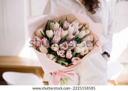 Very nice young woman holding beautiful floral mono composition of fresh pink tulip flowers, cropped photo, bouquet close up