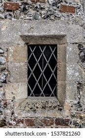 Very old antique small glass window in a solid castle wall with diagonal leading across it.