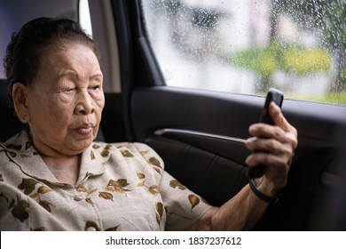 Very Old Asian Passenger Woman Age Between 80 - 90 Years Old Traveling By The Car While Raining And Using A Video Call. Cheerful Retired Woman In A Private Car Portrait With Copy Space.