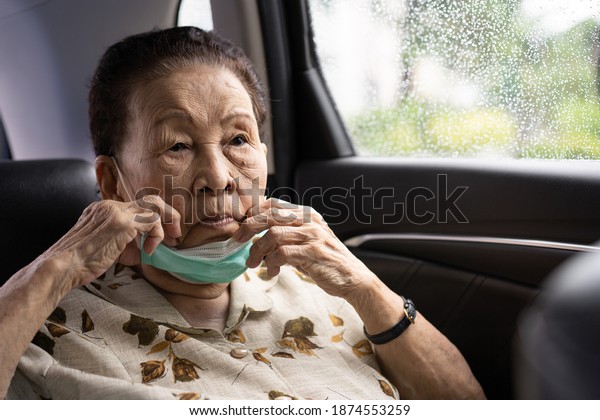 Very old Asian woman age between 80 -90 years\
old travel by the personal car, elder woman using protective face\
mask during traveling. Coronavirus or COVID-19 pandemic concept.\
COVID19 outbreak.