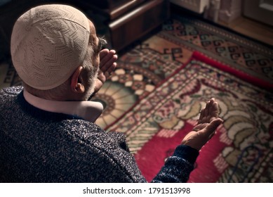 Very old bearded Muslim man at his 80's with a prayer cap praying to Allah at his home on his prayer in Ramadan month