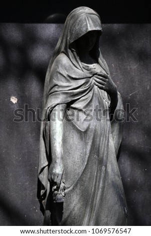 A very old culpture of a grieving mother, face is in shadow. An angel whose face is completely in the shadow. An angel without a face.
